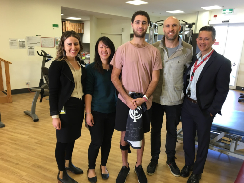 Chris Judd standing with patient Joe and medical team